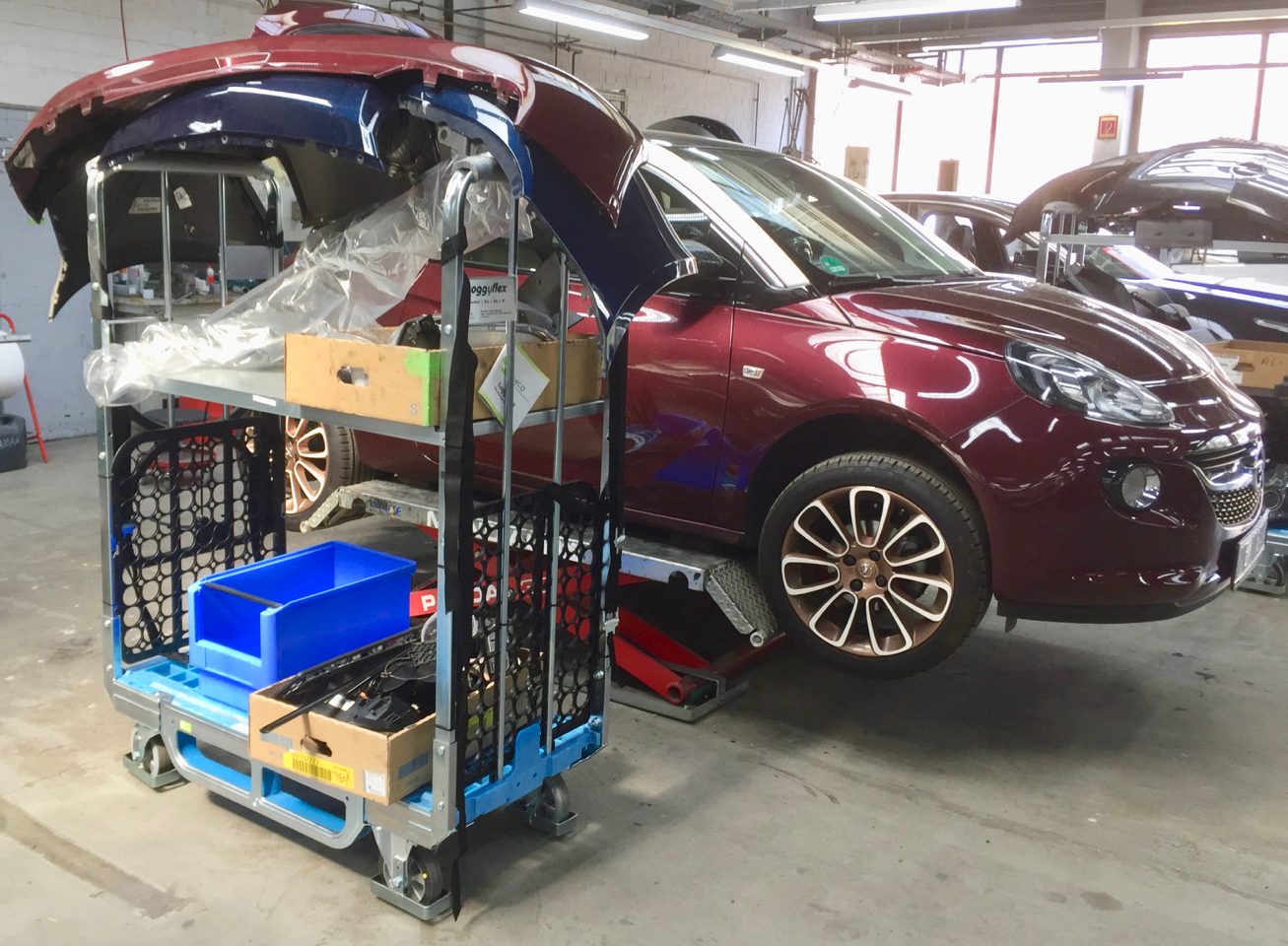 Loggyflex Duo with tailgate parts and sorting boxes next to a vehicle in the body shop