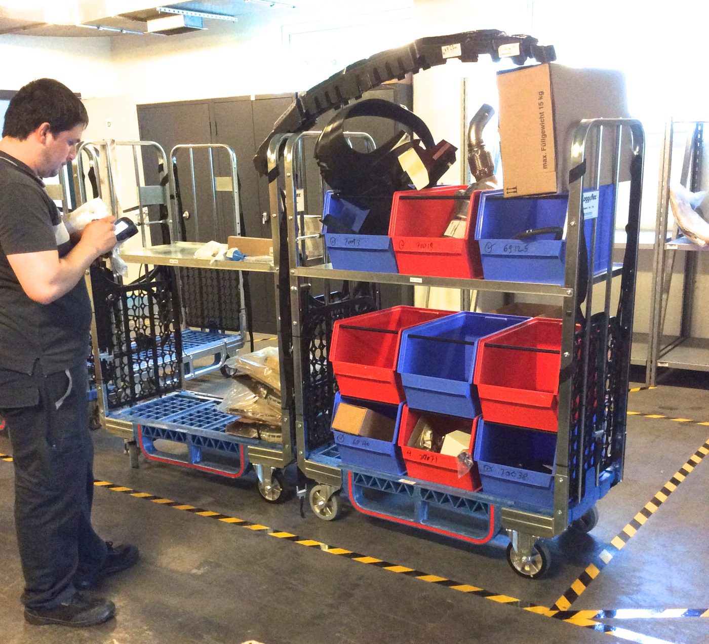Employee picking parts into sorting boxes on two Loggyflex Duo trolleys