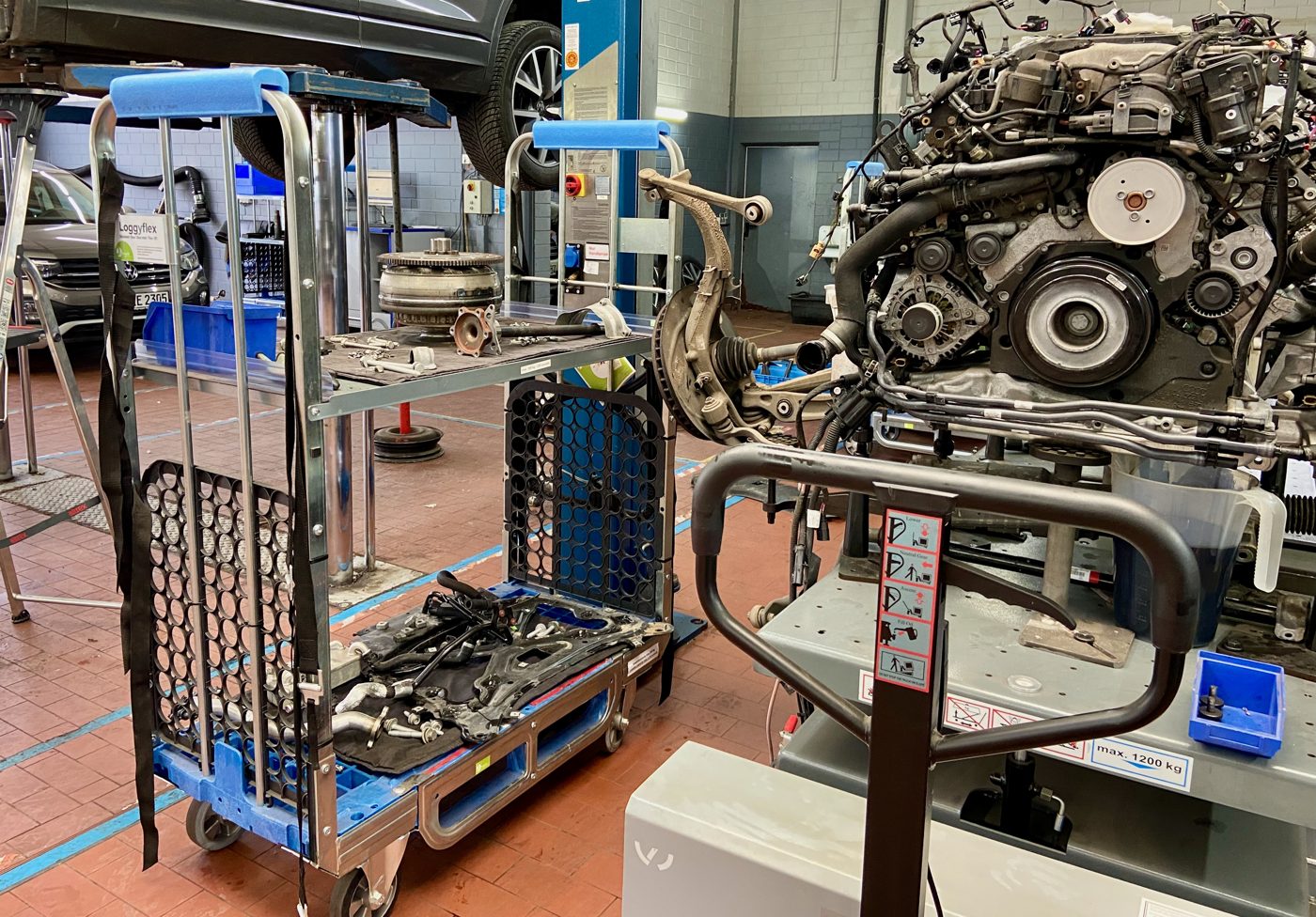 Loggyflex Duo next to a removed engine with torque converter, bolts and axle parts on the intermediate shelf